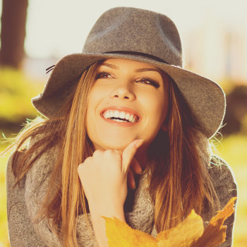 a woman in a hat laughs in the rays of the sun