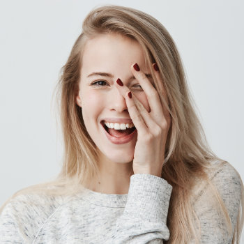 laughing young woman covers her face with her hand