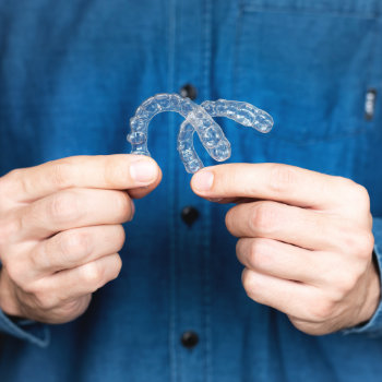 young man holding an invisible tooth alignment retainer in his hands